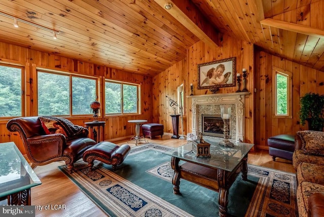 living room featuring wooden walls, vaulted ceiling with beams, a fireplace, wood ceiling, and light wood-style floors