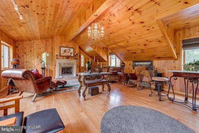 living area featuring lofted ceiling with beams, wood ceiling, plenty of natural light, and wood finished floors