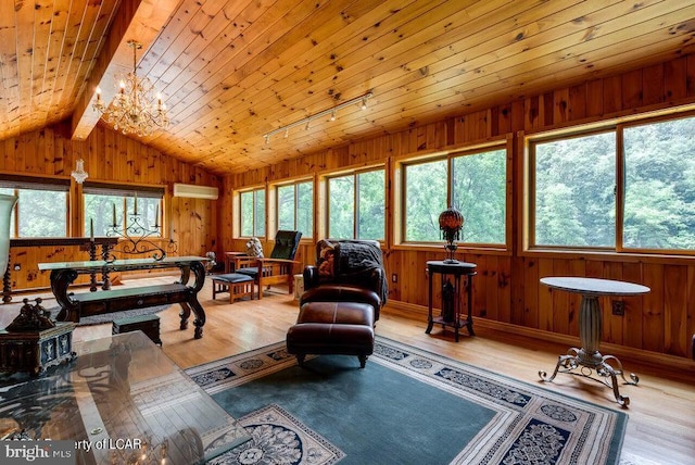 living area with wood finished floors, lofted ceiling with beams, a healthy amount of sunlight, and wood walls