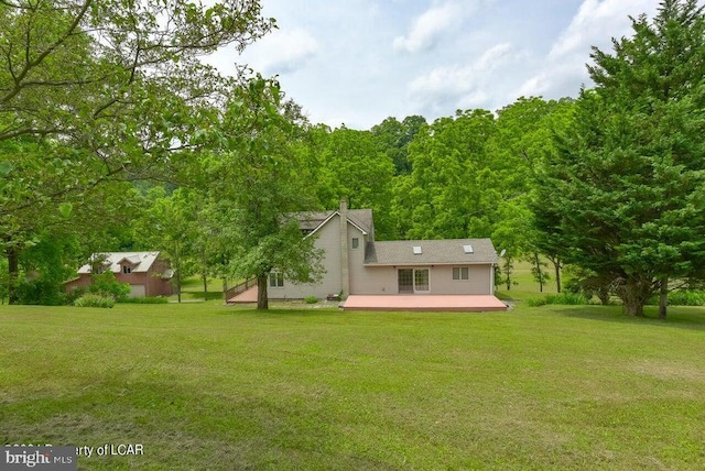 rear view of house featuring a yard, a chimney, and a deck