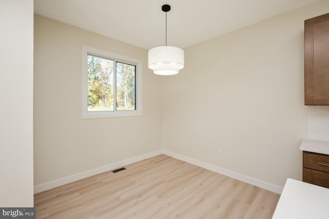 unfurnished dining area featuring visible vents, baseboards, and light wood finished floors