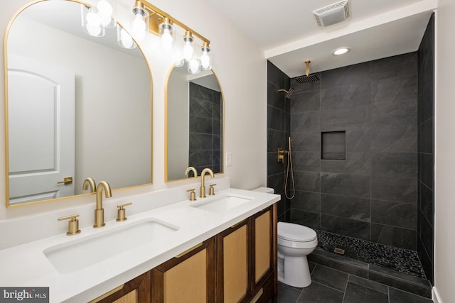 bathroom featuring a sink, visible vents, toilet, and a tile shower