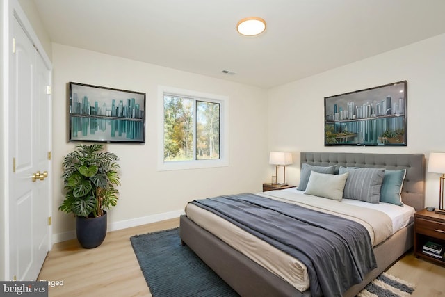 bedroom with visible vents, baseboards, and wood finished floors