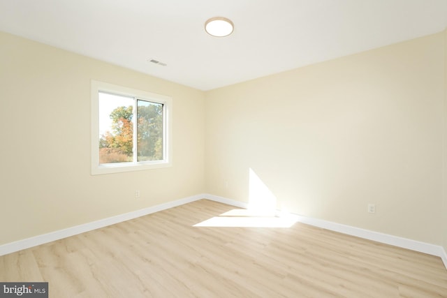 unfurnished room with light wood finished floors, visible vents, and baseboards