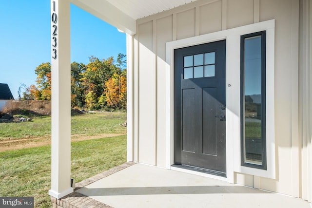 view of exterior entry with a yard and board and batten siding