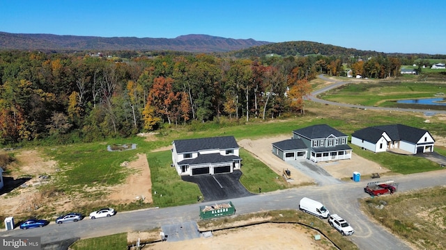 drone / aerial view featuring a view of trees and a water and mountain view