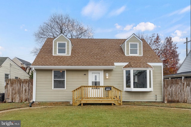 cape cod house featuring roof with shingles, a front yard, and fence