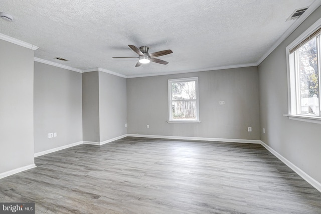 empty room with plenty of natural light, wood finished floors, and visible vents