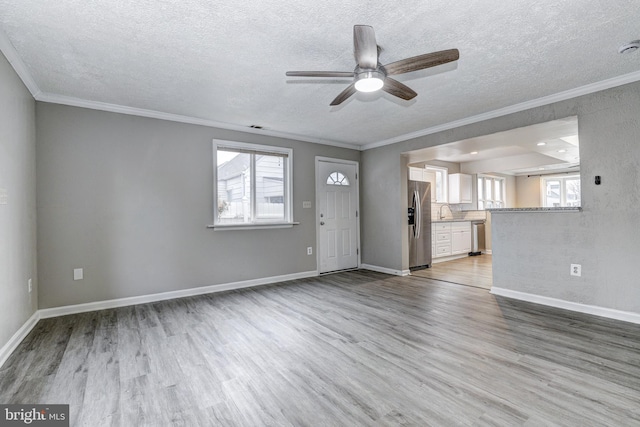 unfurnished living room with plenty of natural light, wood finished floors, and ornamental molding