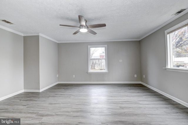 spare room with visible vents, a healthy amount of sunlight, and wood finished floors