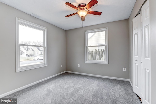 unfurnished bedroom with multiple windows, carpet, baseboards, and ceiling fan