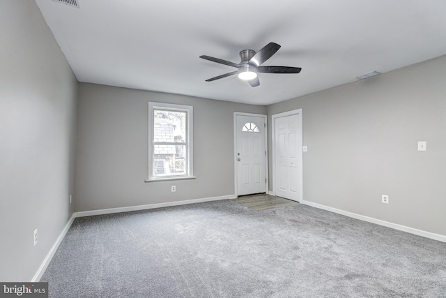 carpeted spare room featuring baseboards, visible vents, and ceiling fan