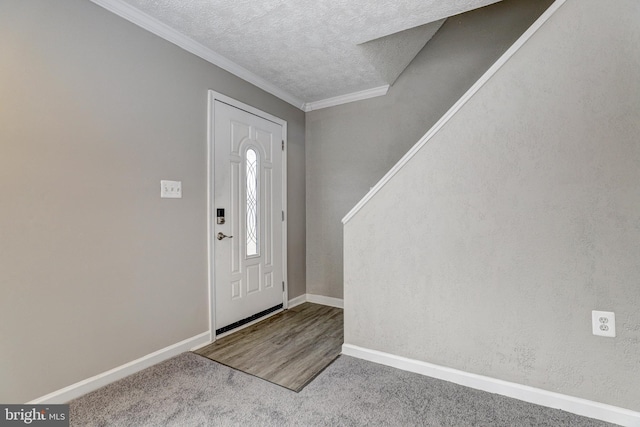 entryway featuring a textured ceiling, wood finished floors, carpet floors, crown molding, and baseboards