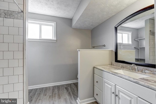 bathroom featuring vanity, wood finished floors, baseboards, a textured ceiling, and toilet