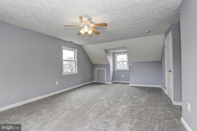 bonus room featuring baseboards, carpet, vaulted ceiling, a textured ceiling, and a ceiling fan