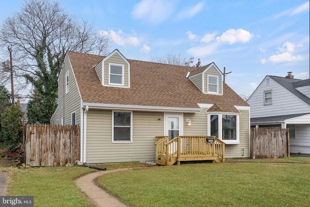 cape cod house featuring a shingled roof, a front yard, and fence