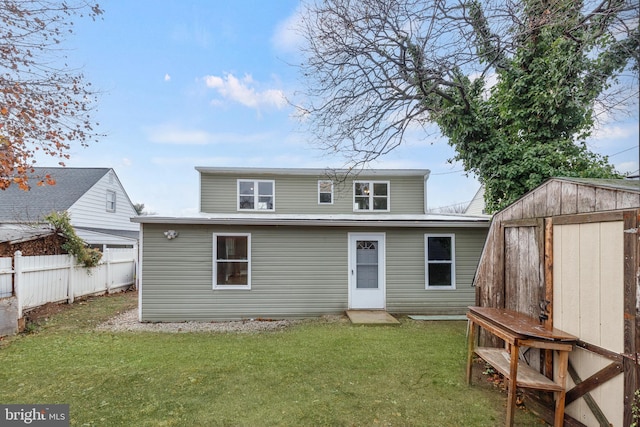 rear view of house featuring an outdoor structure, a yard, fence, and a shed