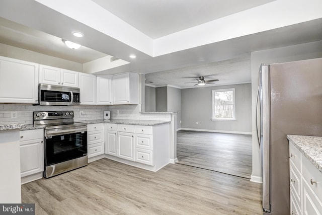 kitchen featuring backsplash, white cabinets, stainless steel appliances, and light wood-type flooring