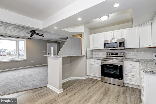 kitchen featuring white cabinets, light stone countertops, baseboards, and stainless steel appliances