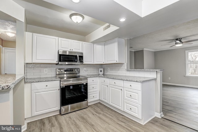 kitchen with light wood finished floors, white cabinets, appliances with stainless steel finishes, and a peninsula