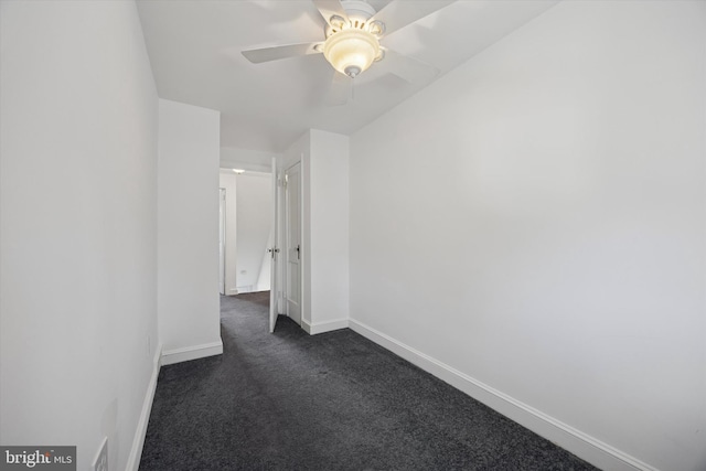 empty room with a ceiling fan, baseboards, and dark colored carpet