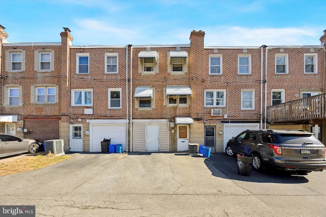 view of property with central air condition unit, driveway, and an attached garage