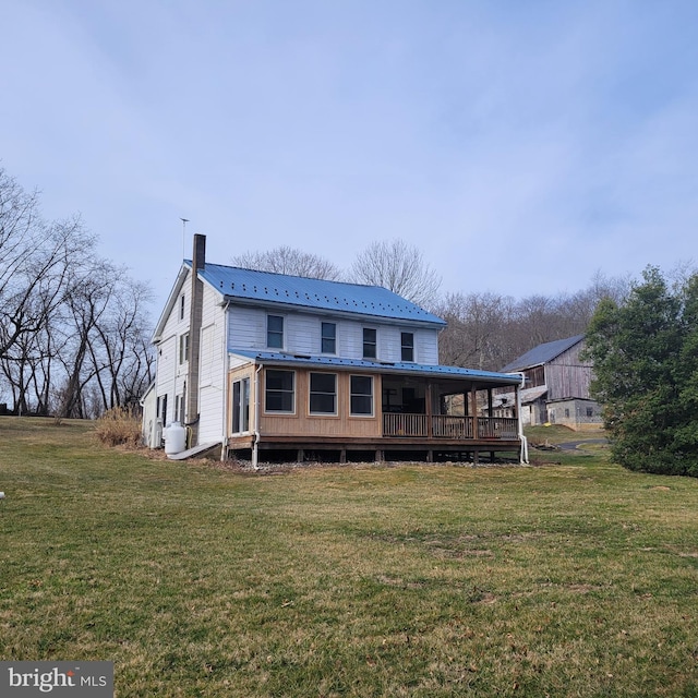 back of house featuring metal roof, a lawn, a deck, and a chimney