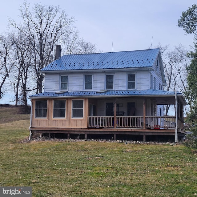 country-style home with a front lawn, a chimney, and metal roof