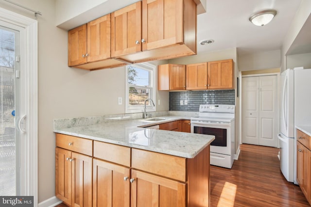 kitchen with white appliances, visible vents, a sink, dark wood-type flooring, and tasteful backsplash