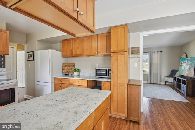 kitchen with brown cabinets, dark wood-style floors, white appliances, baseboards, and light stone countertops