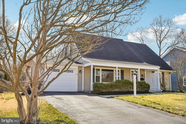 view of front of property featuring aphalt driveway, an attached garage, a shingled roof, and a front yard