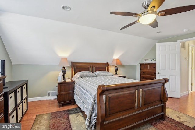 bedroom with visible vents, baseboards, lofted ceiling, and wood finished floors