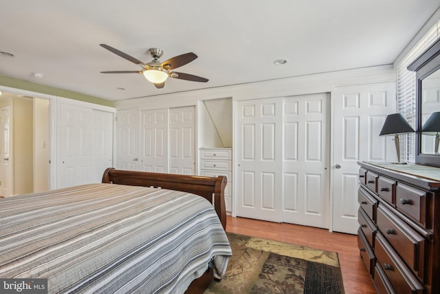 bedroom with a ceiling fan, multiple closets, and light wood-type flooring