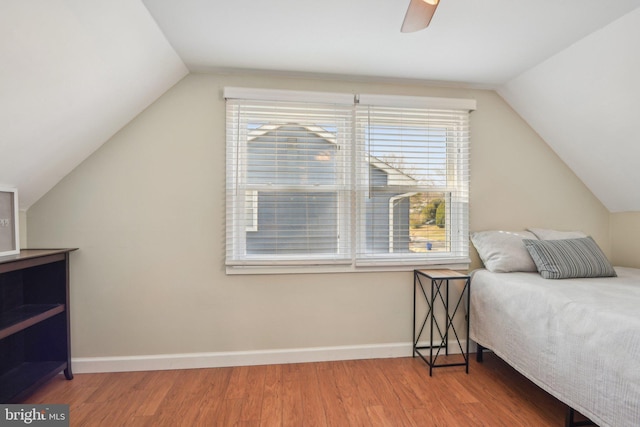 bedroom with a ceiling fan, lofted ceiling, baseboards, and wood finished floors