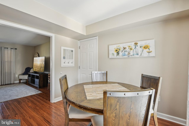 dining space with baseboards and dark wood-type flooring