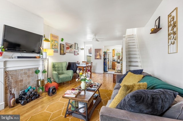 living area with a ceiling fan, wood finished floors, and a fireplace