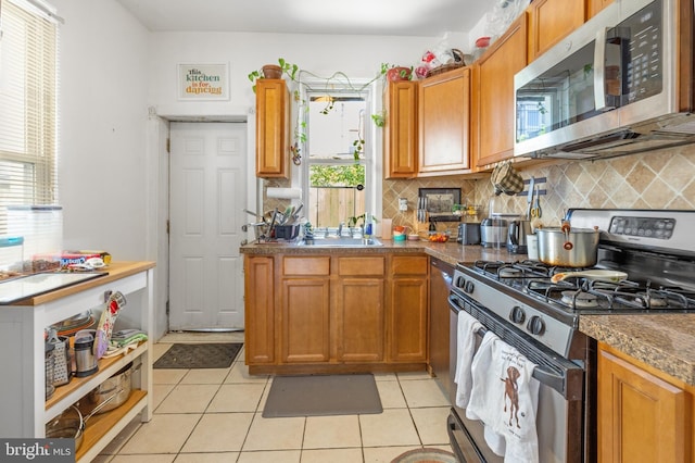 kitchen featuring a sink, tasteful backsplash, light tile patterned flooring, and stainless steel appliances