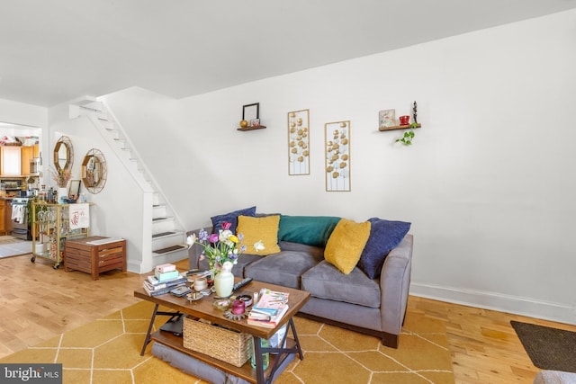 living area featuring stairs, light wood-type flooring, and baseboards