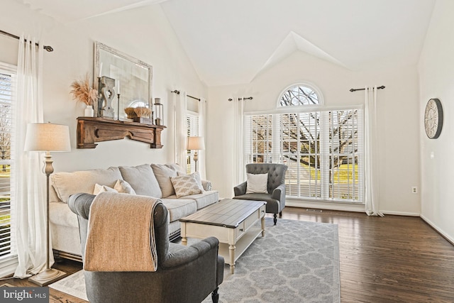 living room with vaulted ceiling, wood finished floors, visible vents, and baseboards