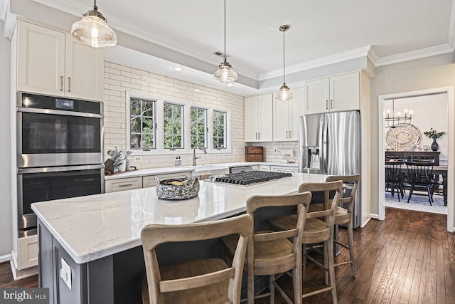 kitchen with stainless steel appliances, dark wood-style floors, ornamental molding, and a center island