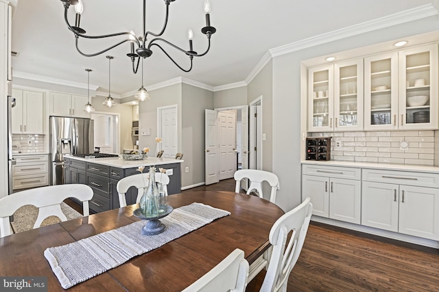 dining room with dark wood-style floors, a notable chandelier, and crown molding