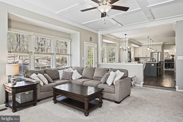 carpeted living area featuring crown molding, plenty of natural light, ceiling fan with notable chandelier, and coffered ceiling