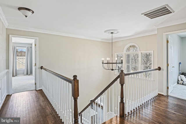 stairway with visible vents, baseboards, ornamental molding, hardwood / wood-style floors, and an inviting chandelier