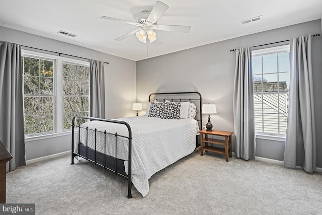 carpeted bedroom with visible vents, multiple windows, and baseboards