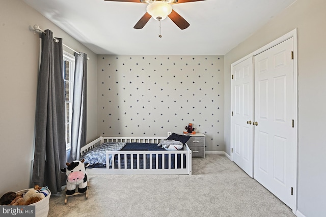 unfurnished bedroom with a closet, carpet flooring, baseboards, and a ceiling fan