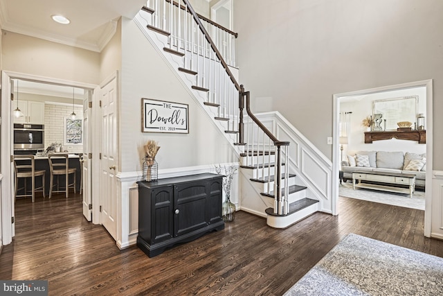 stairs with recessed lighting, crown molding, a high ceiling, and wood finished floors