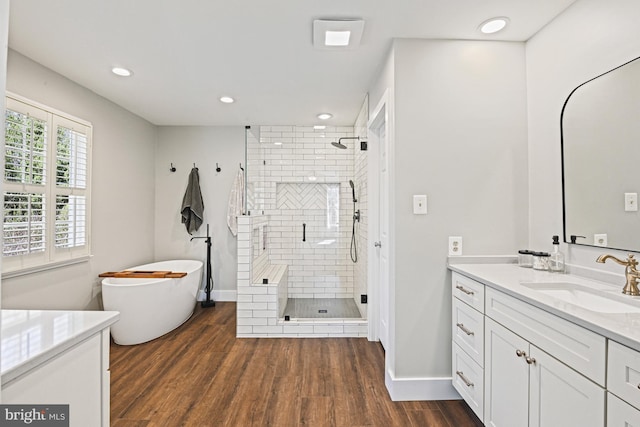 bathroom featuring vanity, wood finished floors, recessed lighting, a freestanding bath, and a shower stall