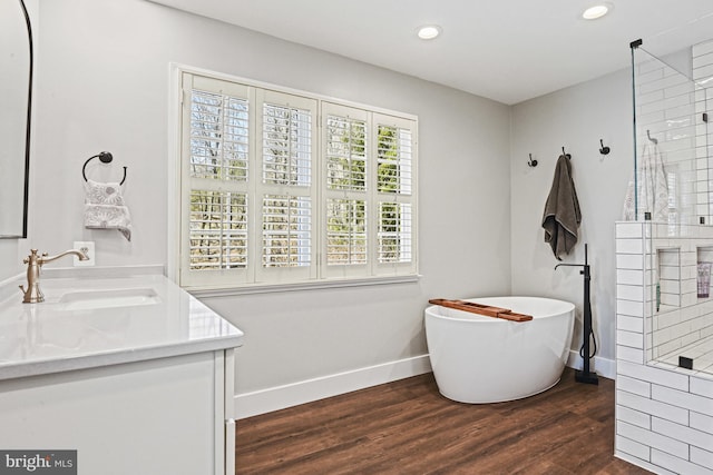 bathroom with wood finished floors, baseboards, tiled shower, recessed lighting, and a freestanding bath