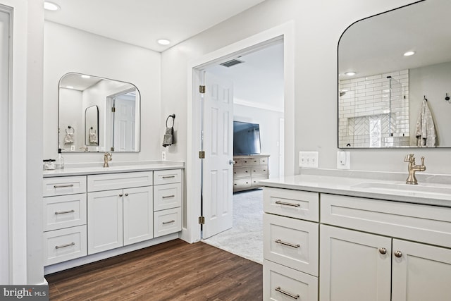 bathroom with a sink, visible vents, two vanities, and wood finished floors