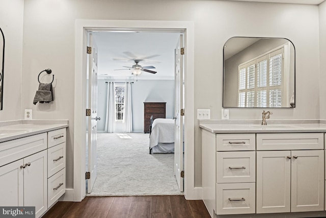 bathroom with crown molding, two vanities, ensuite bathroom, wood finished floors, and a sink